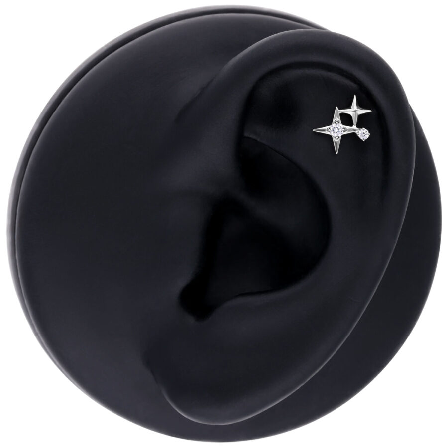 Aplique de piercing de estrella plateada en modelo de oreja negra sobre fondo blanco