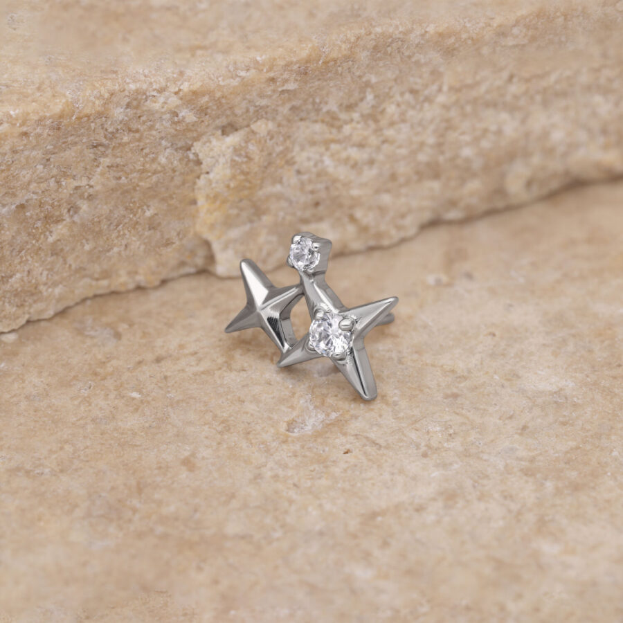 Pieza de estrella plateada con cristal claro sobre fondo de piedra beige