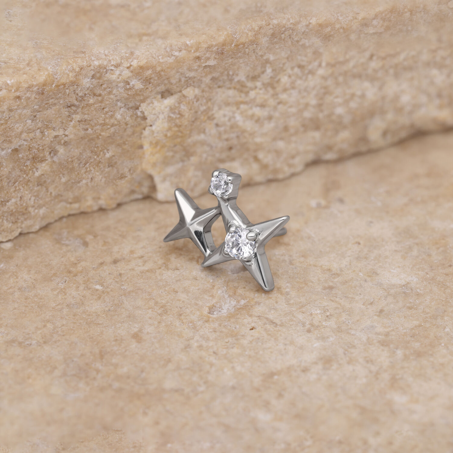 Pieza de estrella plateada con cristal claro sobre fondo de piedra beige