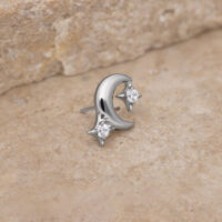 Accesorio de piercing de luna plateada con cristales Accesorio de luna plateada con piedras cristalinas sobre fondo de piedra beige