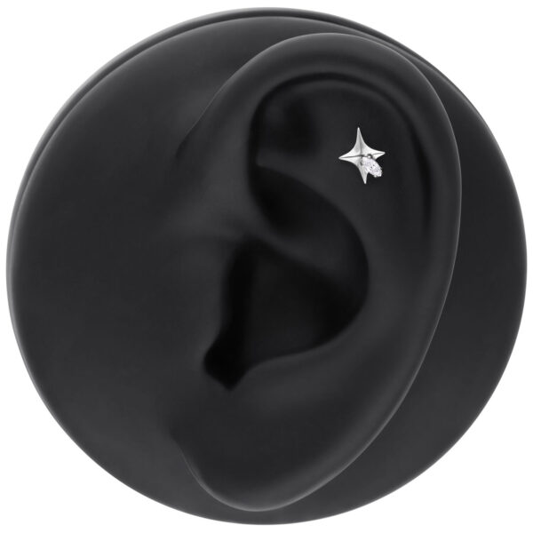 Piercing de estrella plateada con cristal claro en un modelo de oreja negra