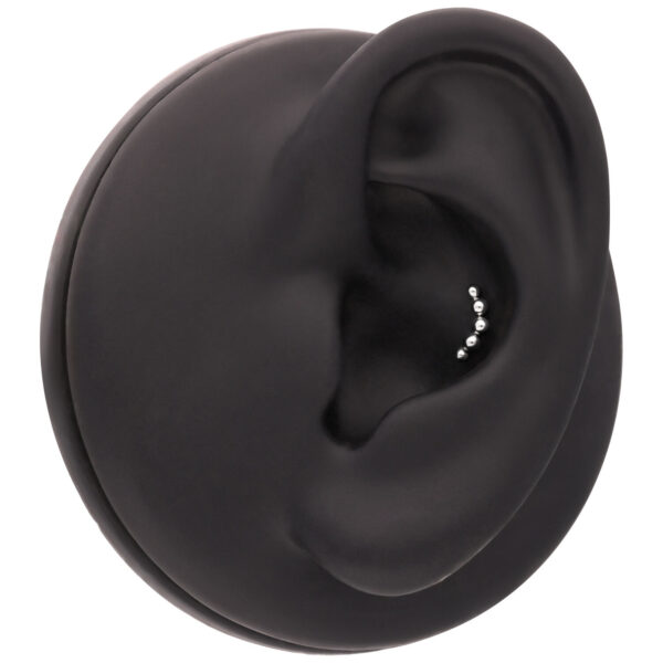 Accesorio negro para piercing de oreja con pequeñas bolas plateadas sobre fondo negro
