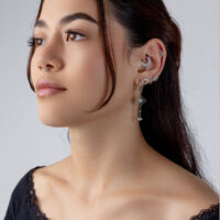Pendiente de cristal plateado con diseño de tiara Mujer con varios piercings plateados en la oreja, incluyendo un adorno de tiara