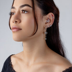 Mujer con varios piercings plateados en la oreja, incluyendo un adorno de tiara