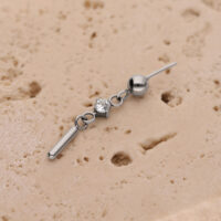 Accesorio de titanio plateado con cristal Accesorio de piercing plateado con cristal redondo y pequeño poste sobre estructura beige