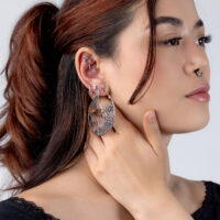 Pendientes de plata con cristales Mujer con pendientes de plata y cristales, fotografiada de lado frente a un fondo blanco