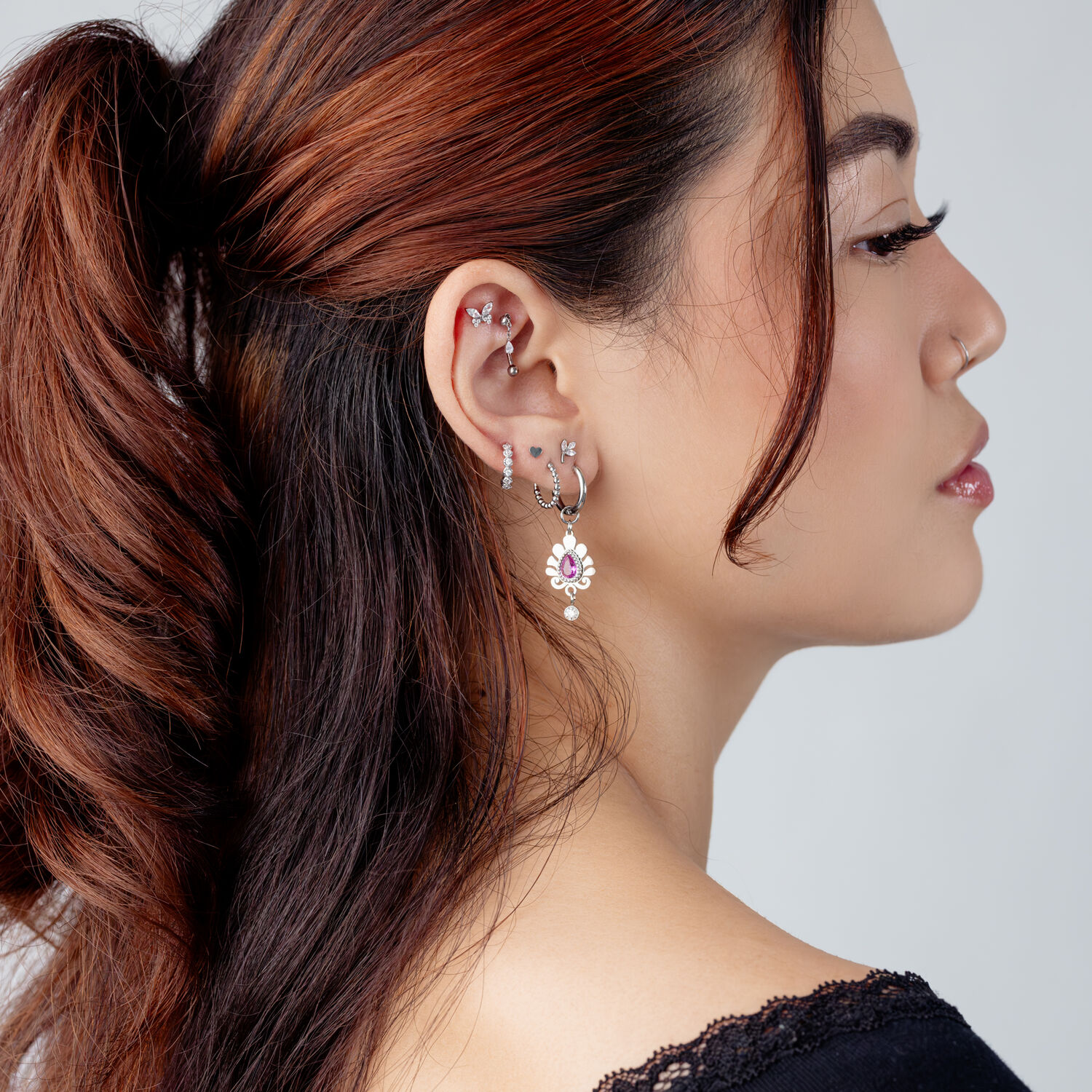 Accesorio de piercing de oreja plateado con cristal Mujer con varios pendientes plateados y un accesorio de cristal en la oreja, vista lateral