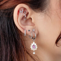 Piercing de Rook de Cristal Ovalado Plateado Oreja con varios piercings plateados, incluyendo un adorno de cristal ovalado
