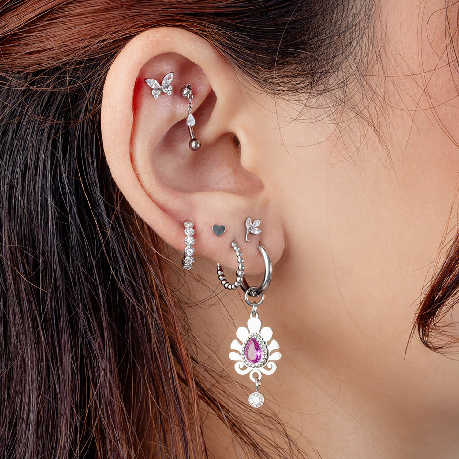 Piercing de Rook de Cristal Ovalado Plateado Oreja con varios piercings plateados, incluyendo un adorno de cristal ovalado