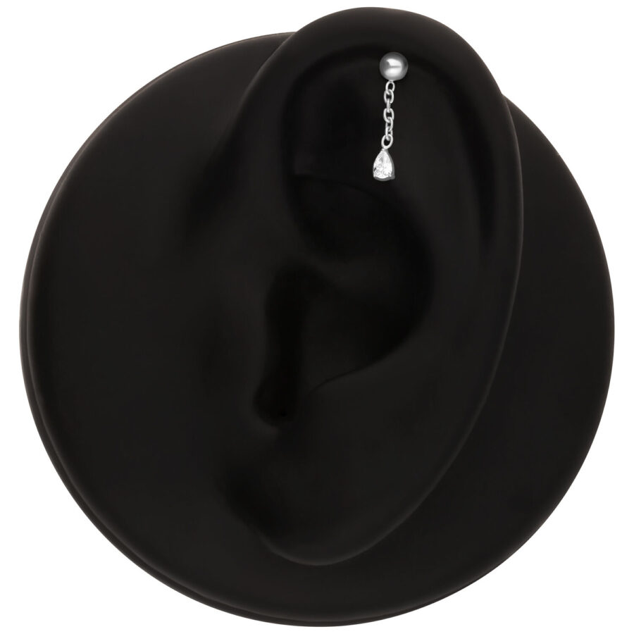 Aplique de piercing plateado con un cristal claro en un modelo de oreja negra