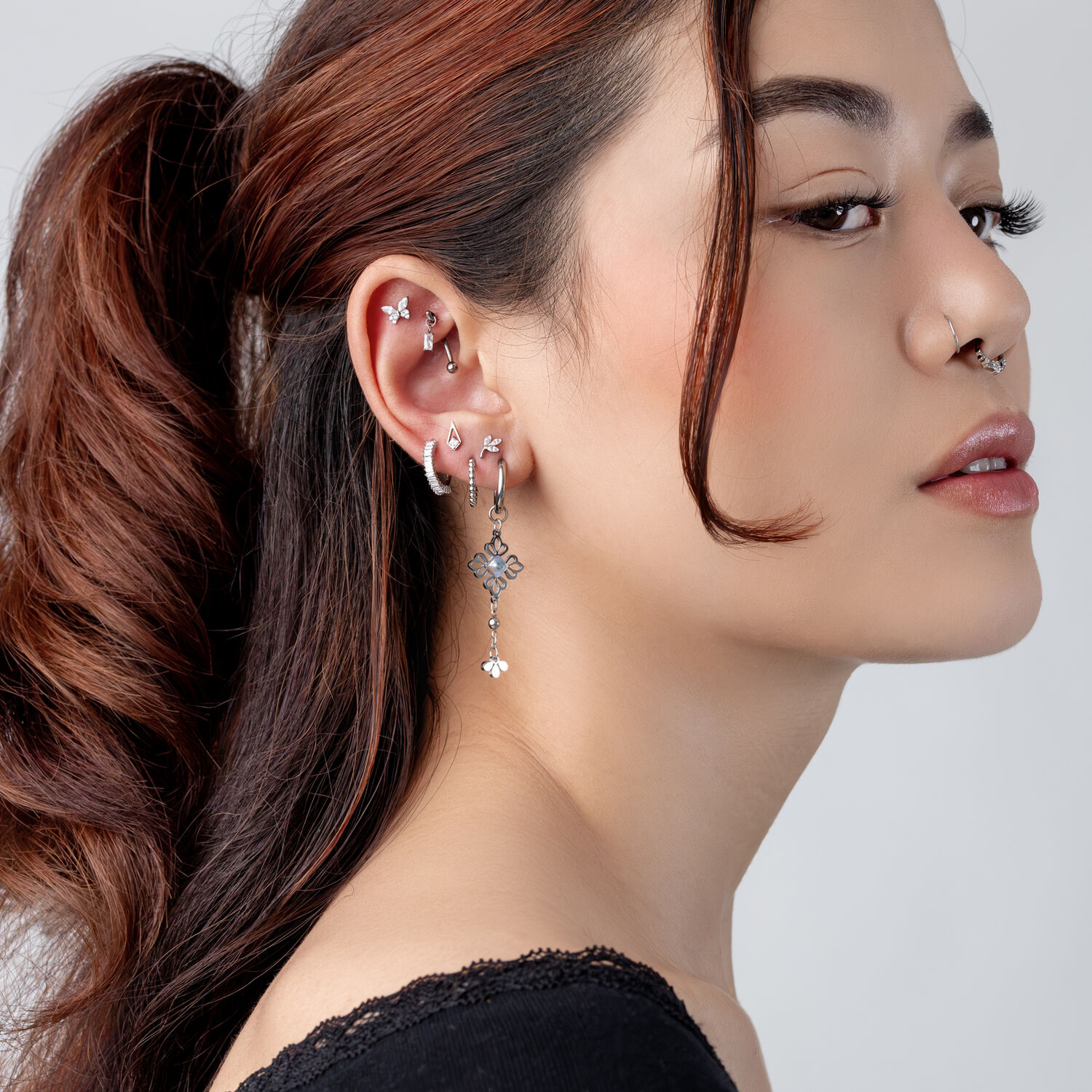 Piercings de titanio plateado con cristales Mujer con varios piercings plateados y cristales sobre fondo claro