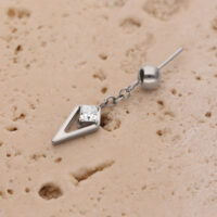 Pieza de Piercing Rook de Cristal Plateado Pieza de piercing plateada con cristal sobre superficie beige texturizada
