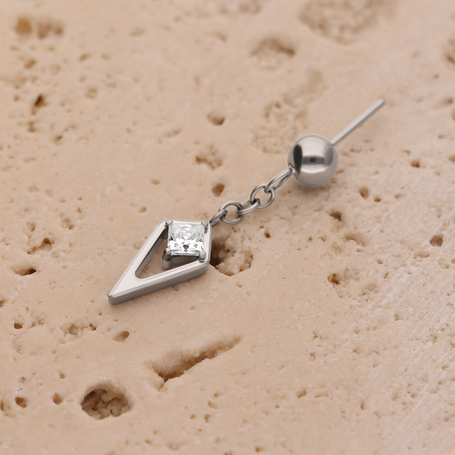 Pieza de Piercing Rook de Cristal Plateado Pieza de piercing plateada con cristal sobre superficie beige texturizada