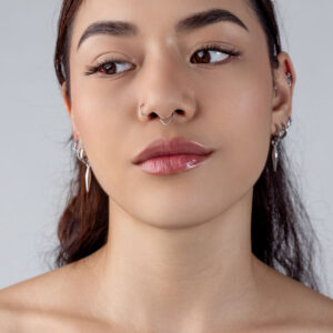 Mujer con Clicker Teardrop plateado en el septum, fondo neutro