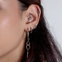 Piercings de plata para orejas con aros Primer plano de una oreja con varios piercings de plata y joyería colgante