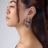 Clicker Half Flower de Titanio Negro Perfil de una persona con varios pendientes, incluyendo un gran Clicker Half Flower negro con diseño floral.
