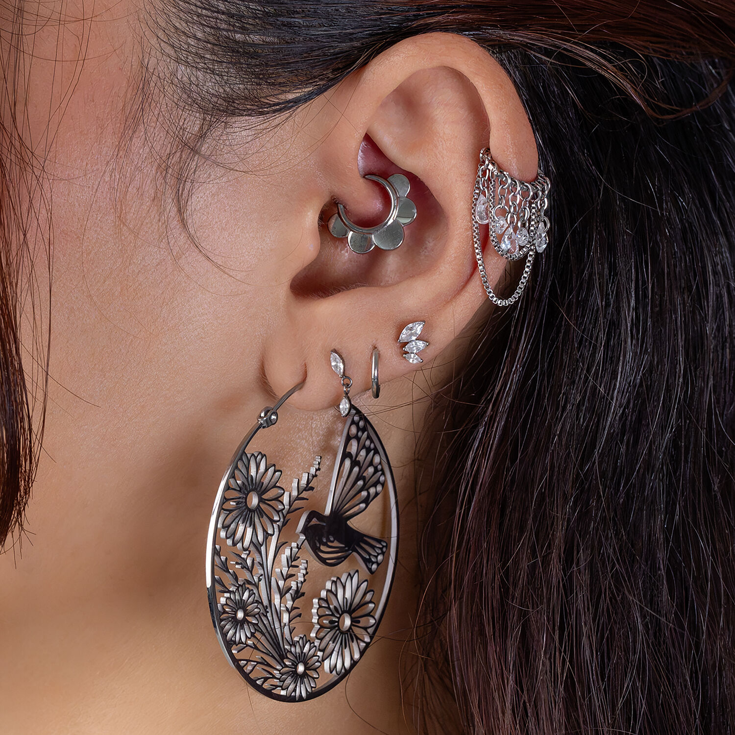 Elegante colgante de piercing floral Gran pendiente delicado en forma de flor en una oreja con varios piercings y un clicker plateado.