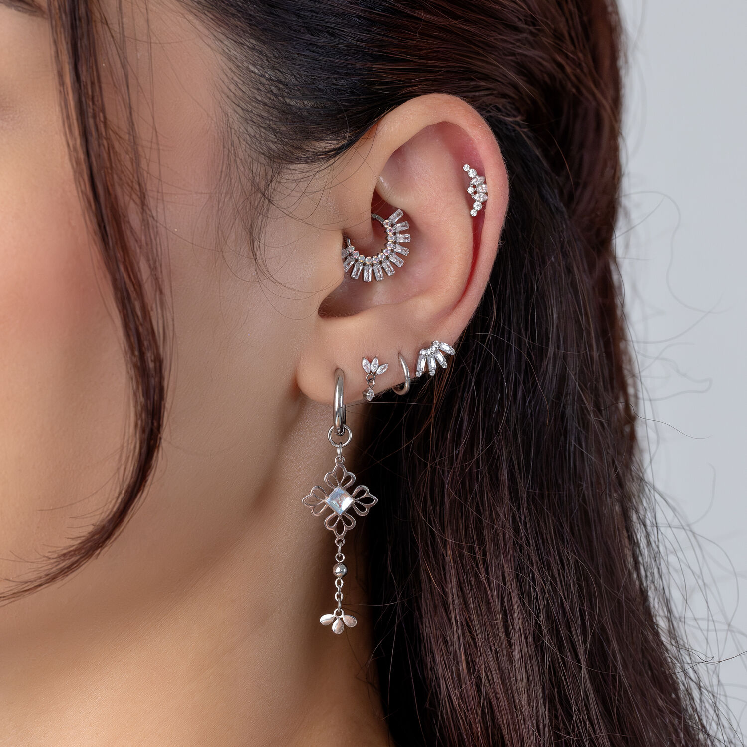 Piercings de plata con cristales Primer plano de una oreja con varios piercings de plata y cristales.