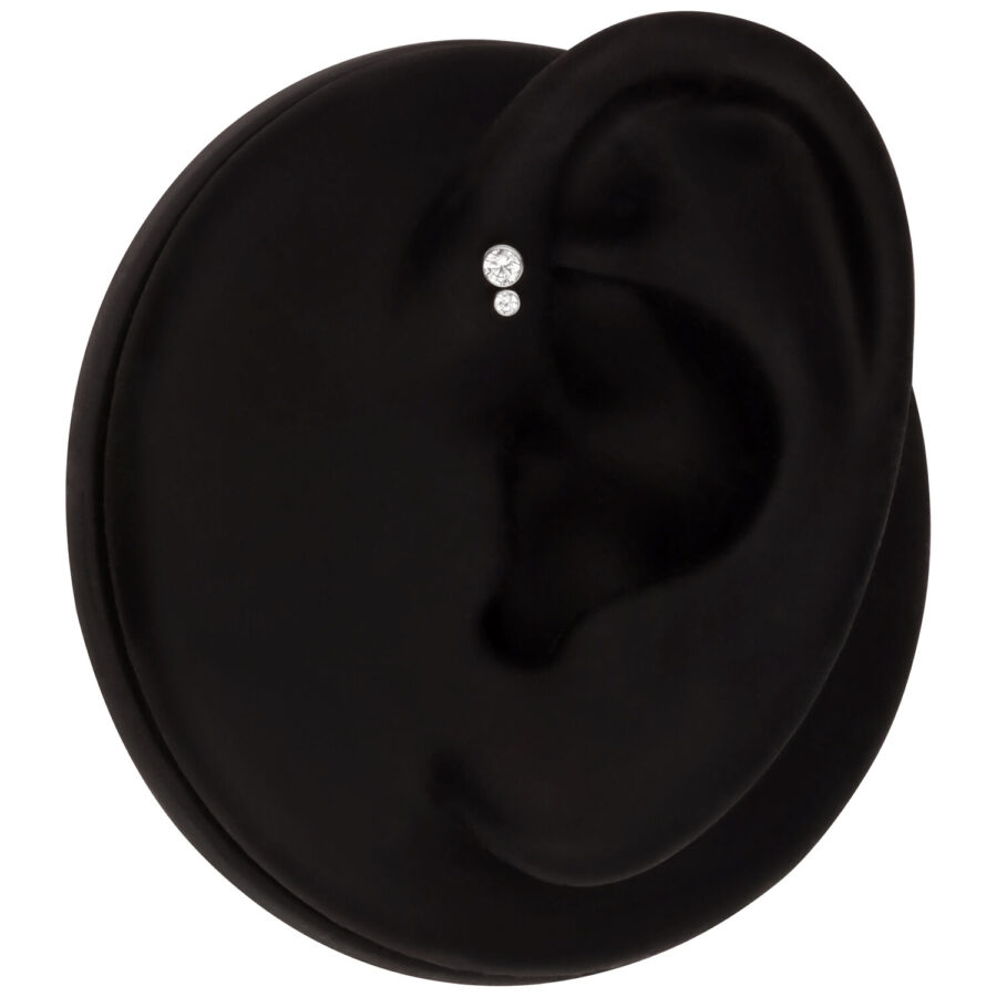 Modelo de oreja negra con un pendiente doble de cristal sobre fondo negro