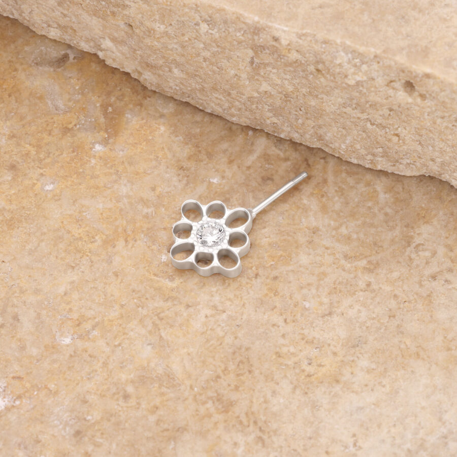 Adorno de flor plateado con cristal claro sobre piedra beige