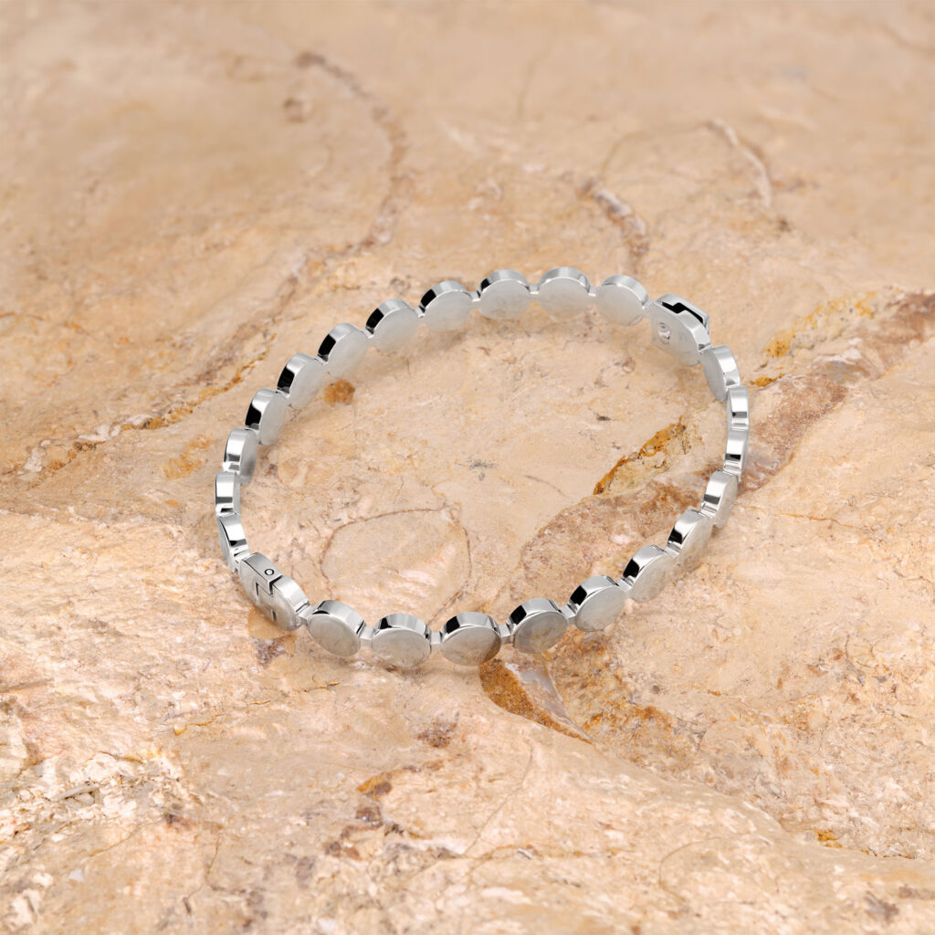Pulsera plateada de acero quirúrgico sobre un fondo de piedra beige
