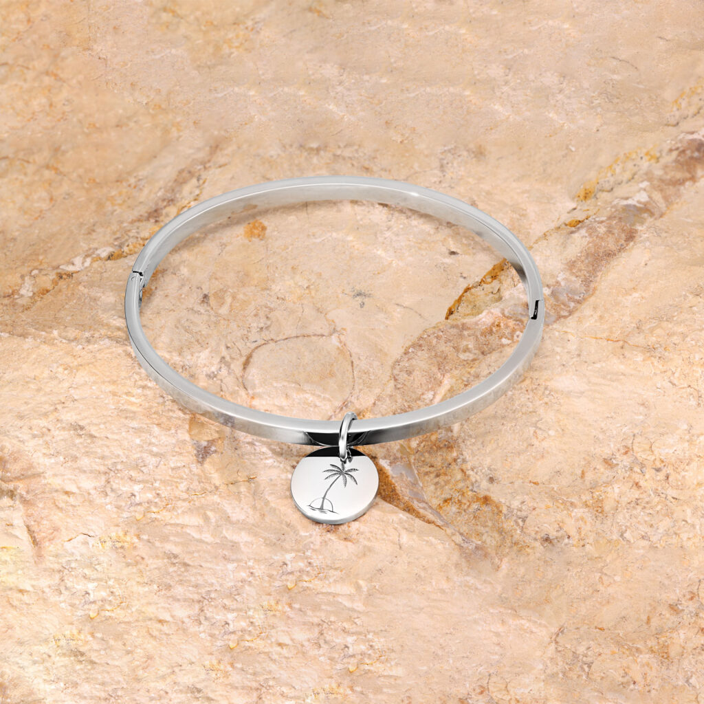 Pulsera de plata con colgante redondo sobre fondo de piedra beige